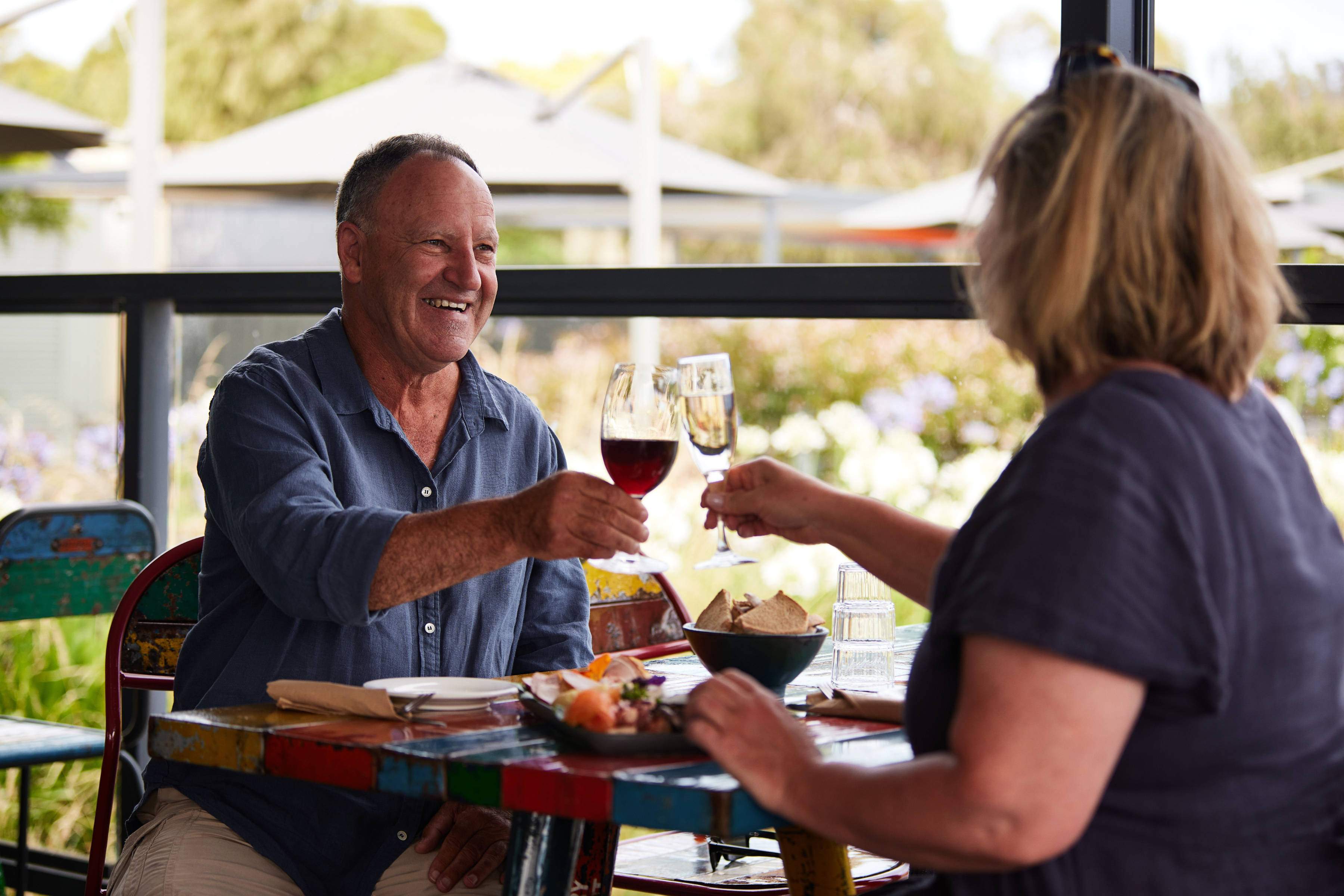 Two people toasting with glasses of wine in an outdoor seating area at Puddleduck Vineyard.